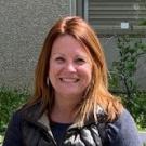 A photo of a woman standing outside, facing the camera and smiling.