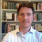 A photo of am an in front of bookshelves.